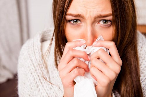 Donna con rinite allergica si soffia il naso