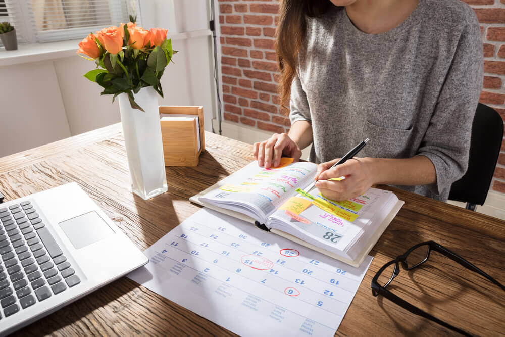 Donna con agenda computer e calendario per pianificare