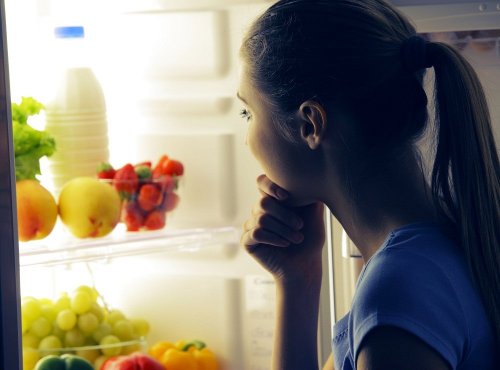 Ragazza davanti al frigorifero sceglie cosa mangiare