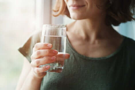 Donna che beve un bicchiere d'acqua.
