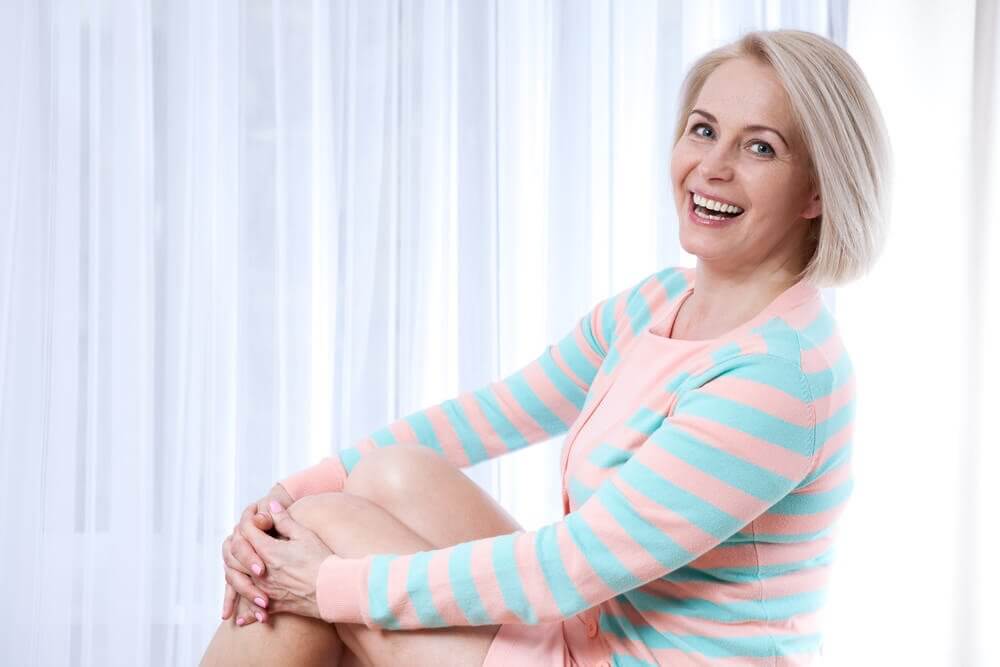 Donna in menopausa con vestito a righe sorridente