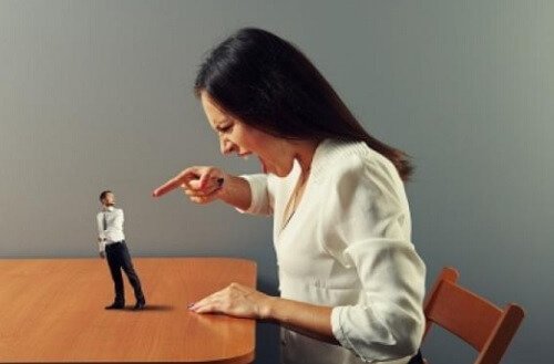 Donna punta il dito su un uomo in miniatura a rappresentare aggressione verbale