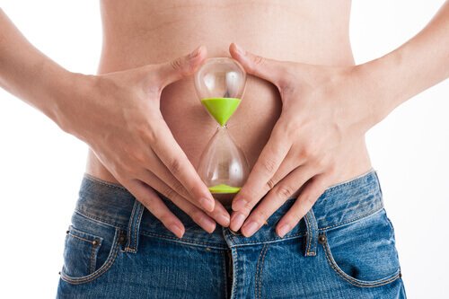 Donna tiene clessidra davanti allo stomaco