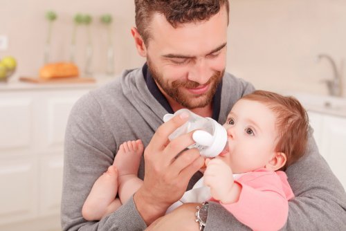 Padre nutre il neonato con il biberon