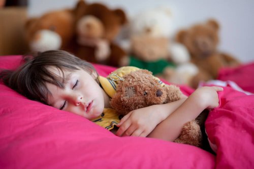 Bambino a letto con un peluche.