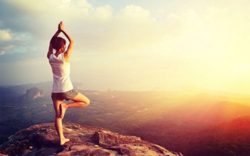 Donna pratica lo yoga sulla cima di una collina