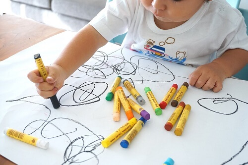 Bambino seduto scarabocchia su foglio