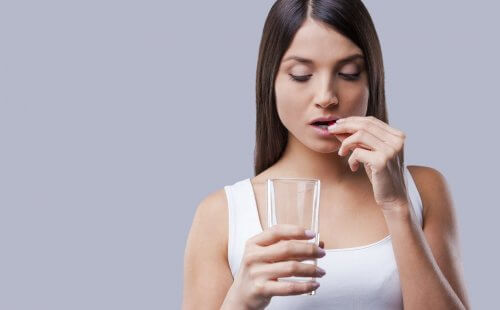 Donna assume pastiglia con bicchiere d'acqua