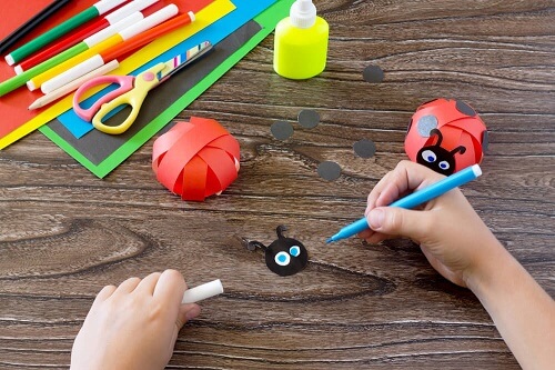 Mani di bambino che fa coccinelle di carta