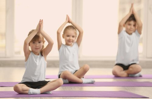 Tre bambini fanno yoga con le mani in alto