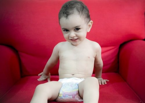 Bambina con il pannolino seduta in poltrona.