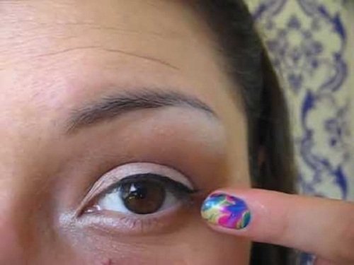 Donna con dito vicino a occhio aperto e unghia colorata