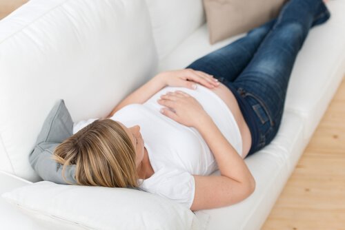 Donna incinta distesa su divano bianco
