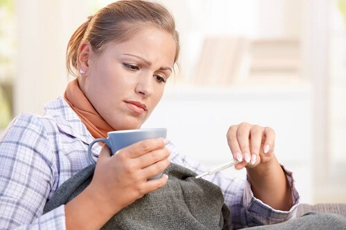 Ragazza controlla termometro con tazza in mano