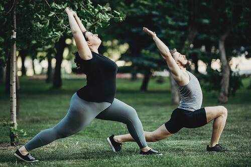 Ragazza obesa e ragazza fanno yoga al parco