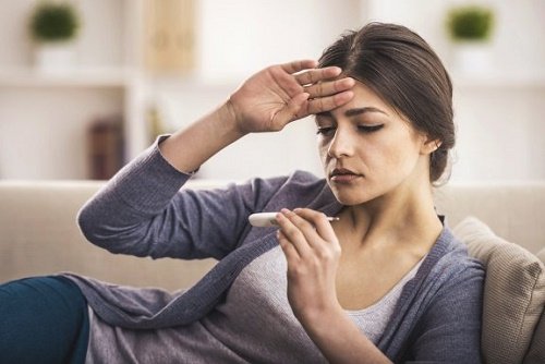 Ragazza su divano legge termometro per febbre