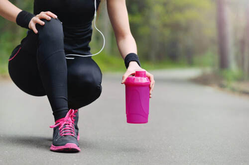 Ragazza sportiva afferra borraccia