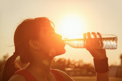 Donna sportiva beve acqua da una bottiglia