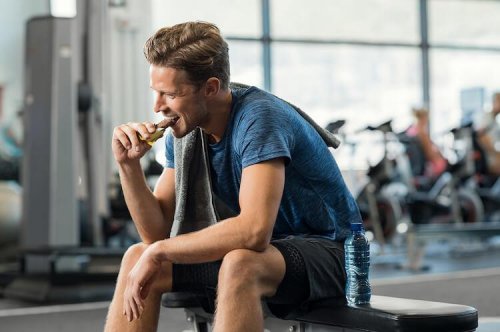 Uomo che mangia una barretta in palestra.