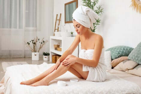 Donna che applica sulle gambe una crema con vitamina E.