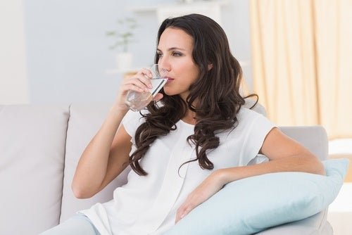 Donna che beve l'acqua per prevenire la cistite dopo i rapporti.