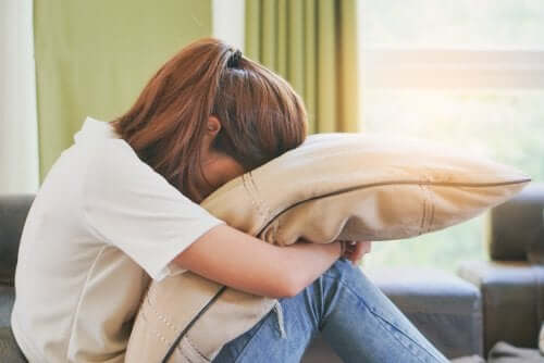 Ragazza che piange contro il cuscino.
