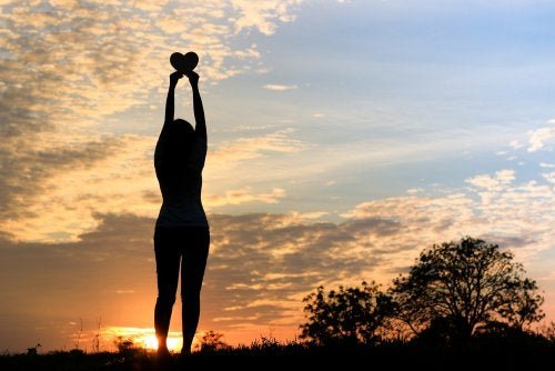 Persona con cuore davanti al tramonto.