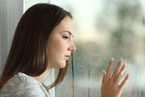 Donna che guarda dalla finestra mentre ripensa alle sue ossessioni mentali