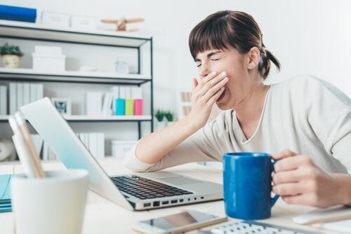 Ragazza tazza che sbadiglia davanti al computer