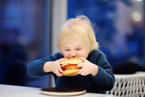 Bambino che addenta un hamburger