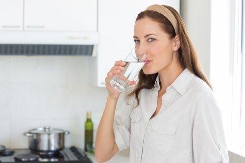 Nutrirsi bene, donna beve un bicchiere d'acqua