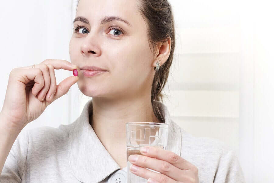 Donna con compressa e bicchiere d'acqua