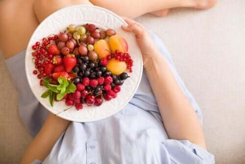 Donna incinta e piatto con frutti di bosco