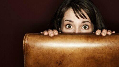 Ragazza spaventata si nasconde dietro un divano
