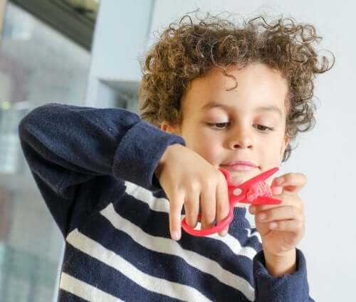 Bambino con forbici e carta.