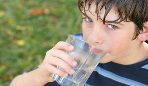 Bambino che beve un bicchiere di acqua