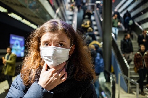 Donna con mascherina e differenza tra influenza, coronavirus e allergia