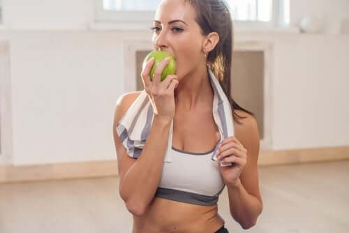 Donna che si allena e mangia una mela