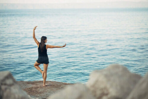 Ragazza che fa yoga davanti al mare e come trasformare la meditazione in un'abitudine