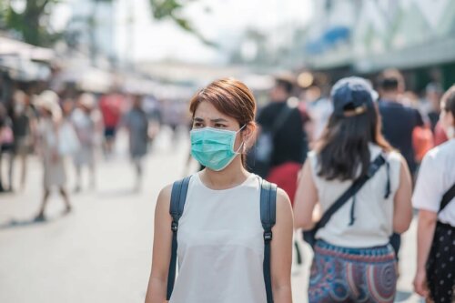 Donna con mascherina in strada affollata
