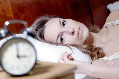 Donna che guarda la sveglia dormire male
