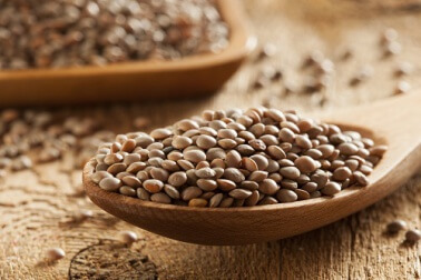 Cucchiaio di legno con lenticchie crude.