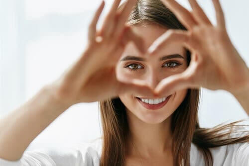 Ragazza con mani a cuore davanti agli occhi.