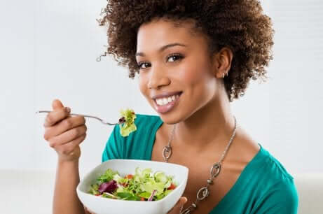 Donna che mangia una insalata.