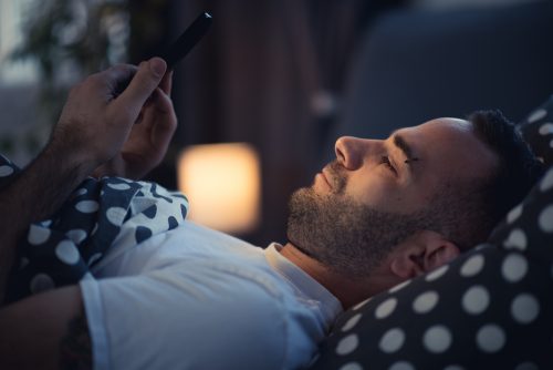 Ragazzo a letto con lo smartphone.