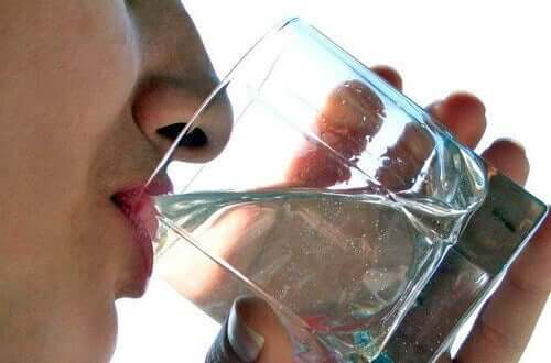 Donna beve un bicchiere d'acqua. L'alimentazione per il diabete di tipo 2 prevede di bere molto.