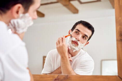 Uomo si fa la barba allo specchio.