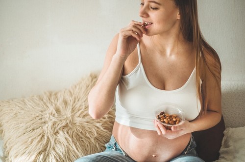 Donna incinta che mangia delle mandorle.