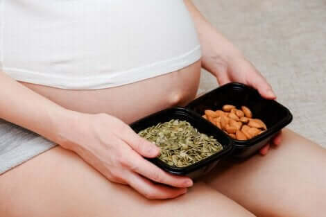 Donna incinta seduta con vaschetta di cibo sulle gambe.