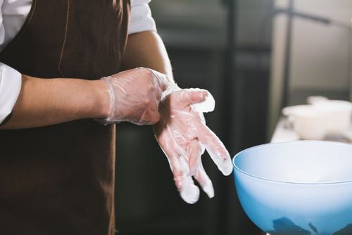 Uso di guanti per evitare la contaminazione crociata degli alimenti.